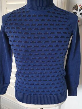 Blue turtleneck sweater with half moon cutouts to black underlay.